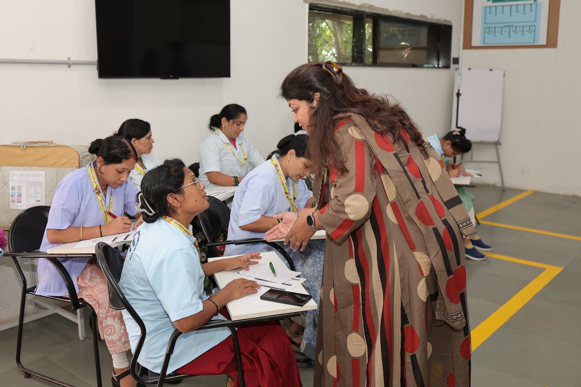 A facilitator leaning in to help a participant at her desk